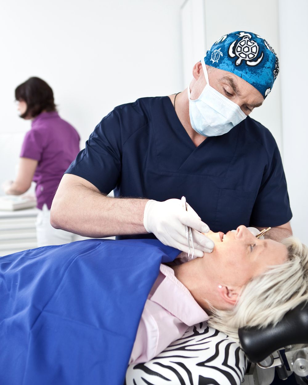 Dr. Knop mit OP-Haube und Mundschutz bei der Behandlung einer Patientin